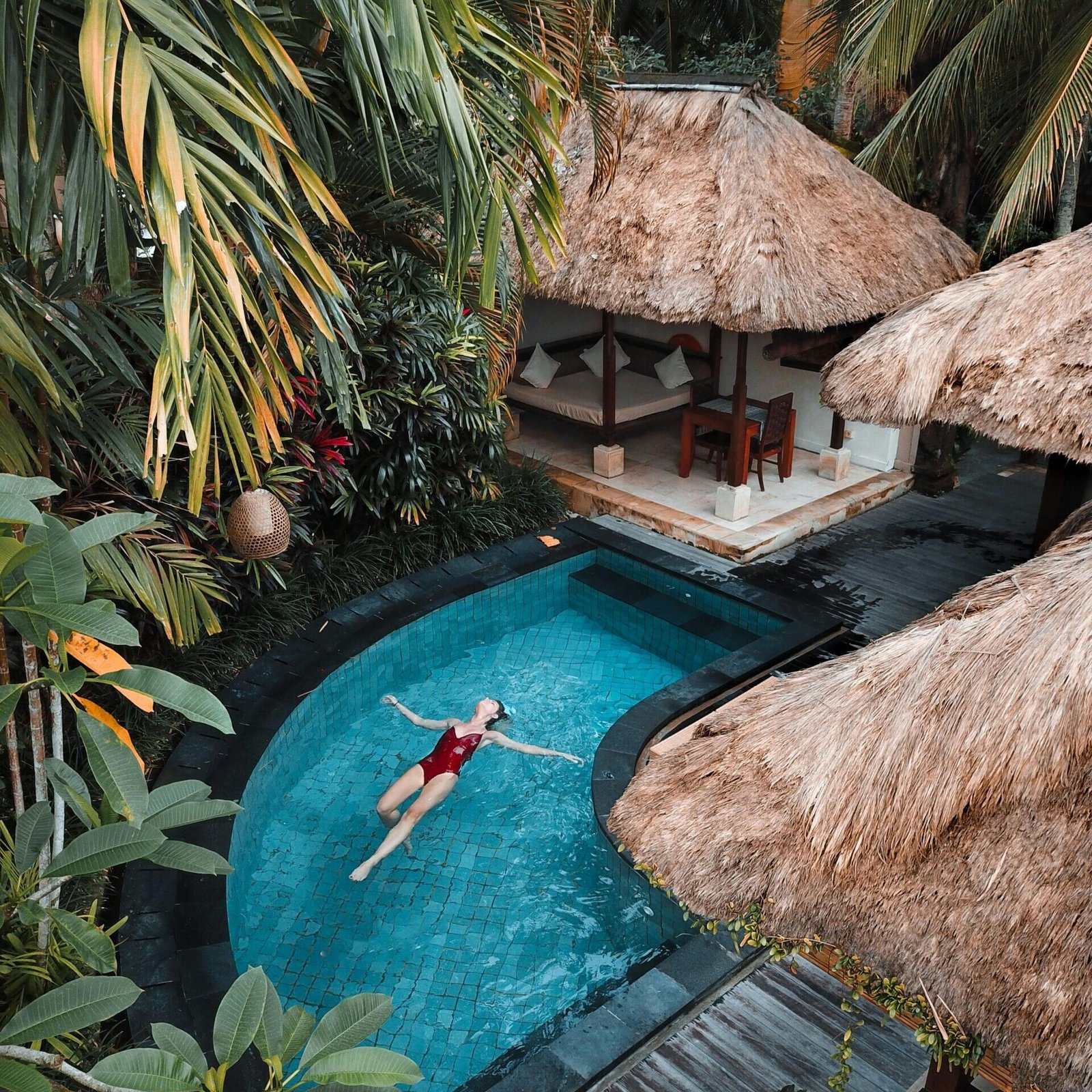 A woman relaxing in a private villa pool, showcasing the luxury hotel booking options available on GlobalTravelGuideX.
